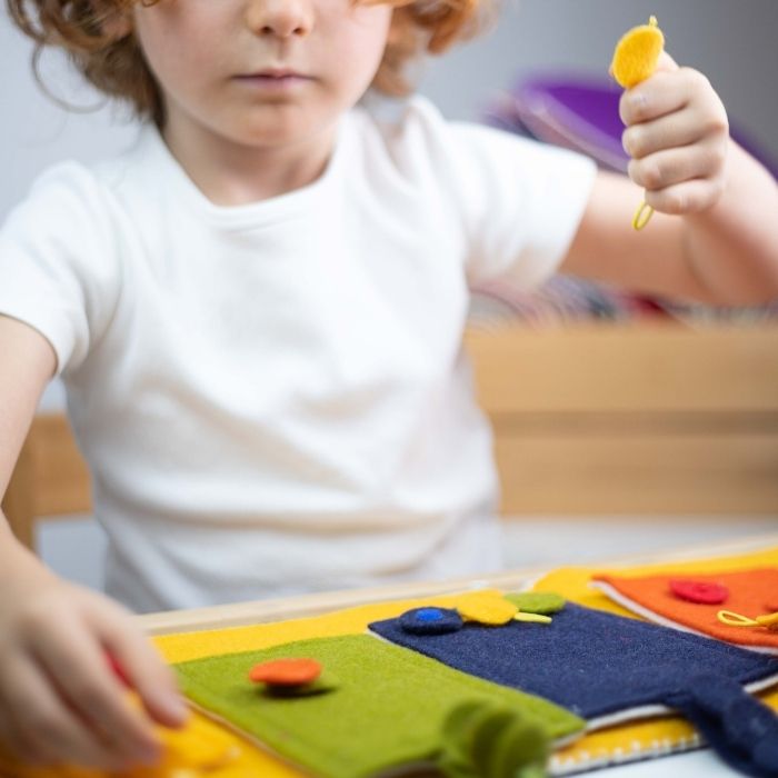 Bambino che gioca con le tessere di Acchiappa il colore, un gioco handmade in feltro lana 96%