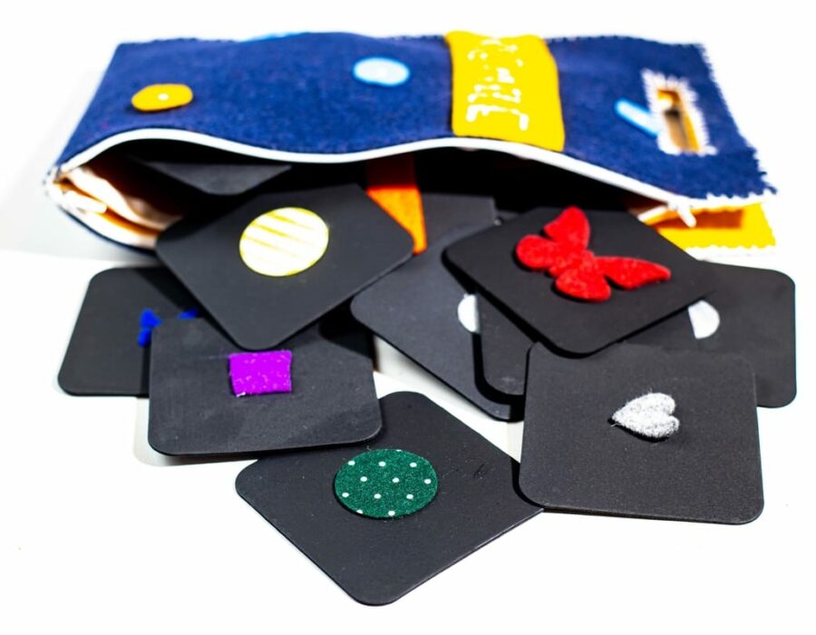 Borsa in feltro lana blu e gialla contenente le tessere nere quadrate del gioco Memory